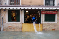 A man removes water from the flooded shop during a period of seasonal high water in Venice, Italy November 15, 2019. REUTERS/Manuel Silvestri