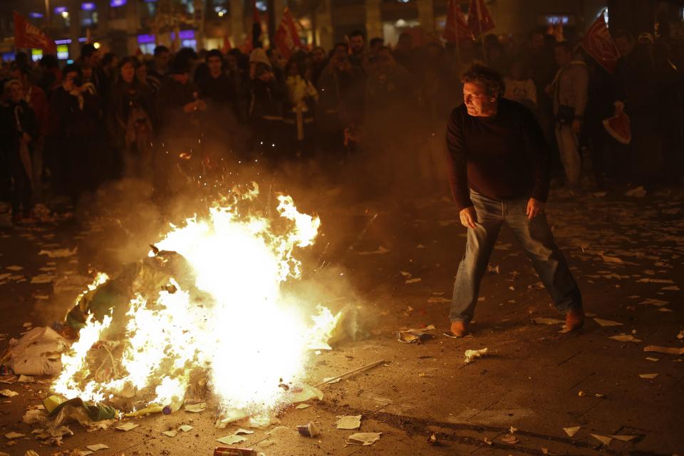 A cleaning worker throws his jacket to the fire during a protest at Madrid's Puerta del Sol square