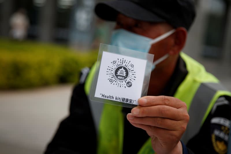 Security guard holds up a QR code for a health app in Beijing