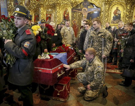 A Ukrainian serviceman reacts near a coffin containing the body of his counterpart Ihor Branovytsky, who was killed in the fighting in eastern Ukraine, during a funeral ceremony in the Mikhailovsky Zlatoverkhy Cathedral (St. Michael's Golden-Domed Cathedral) in central Kiev, in this file picture taken April 3, 2015. REUTERS/Gleb Garanich/Files