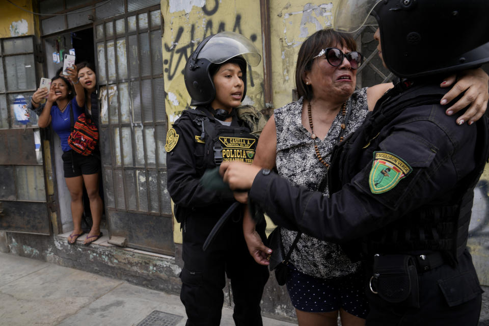 Police confort a neighbor who was harassed by anti-government protesters outside the San Marcos University in Lima, Peru, Saturday, Jan. 21, 2023. Police evicted from the university grounds protesters who arrived from Andean regions seeking the resignation of President Dina Boluarte, the release from prison of ousted President Pedro Castillo and immediate elections. (AP Photo/Martin Mejia)