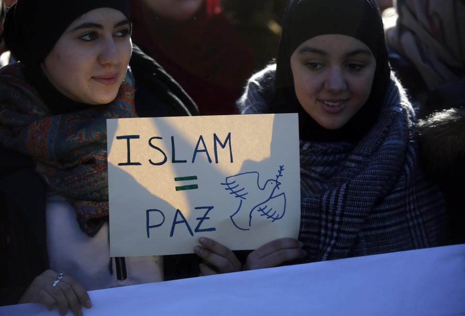 Two young women hold a placard that reads "Islam = Peace" during a rally by members of the Muslim community of Madrid outside Madrid's Atocha train station