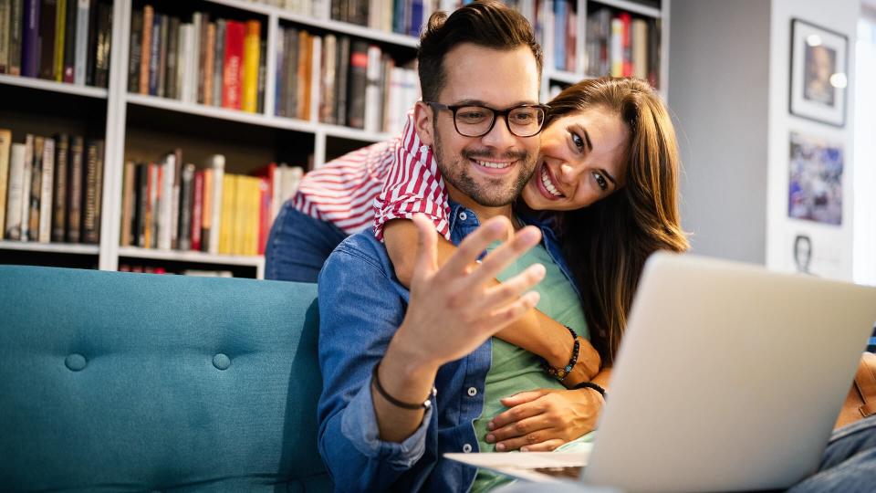 Couple relaxing together in sofa with laptop pc having fun.