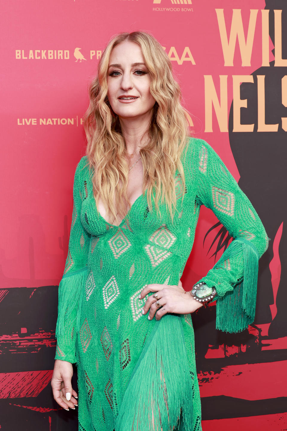Woman in a green dress with fringe details posing on the red carpet