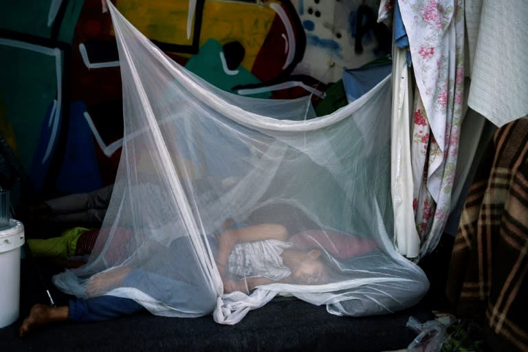 Una niña migrante duerme protegida con una mosquitera el 10 de agosto de 2016 en el antiguo aeropuerto internacional de Atenas, utilizado como campamento temporal (Angelos Tzortzinis)