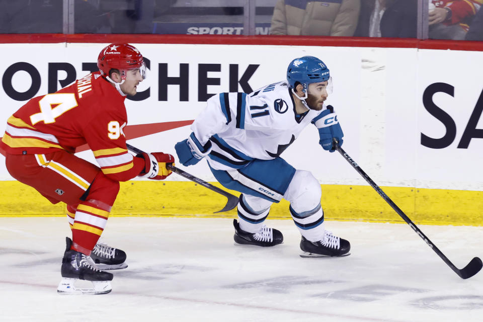 San Jose Sharks' Luke Kunin, right, and Calgary Flames' Brayden Pachal, left, watch a play during first-period NHL hockey game action in Calgary, Alberta, Thursday, Feb. 15, 2024. (Larry MacDougal/The Canadian Press via AP)