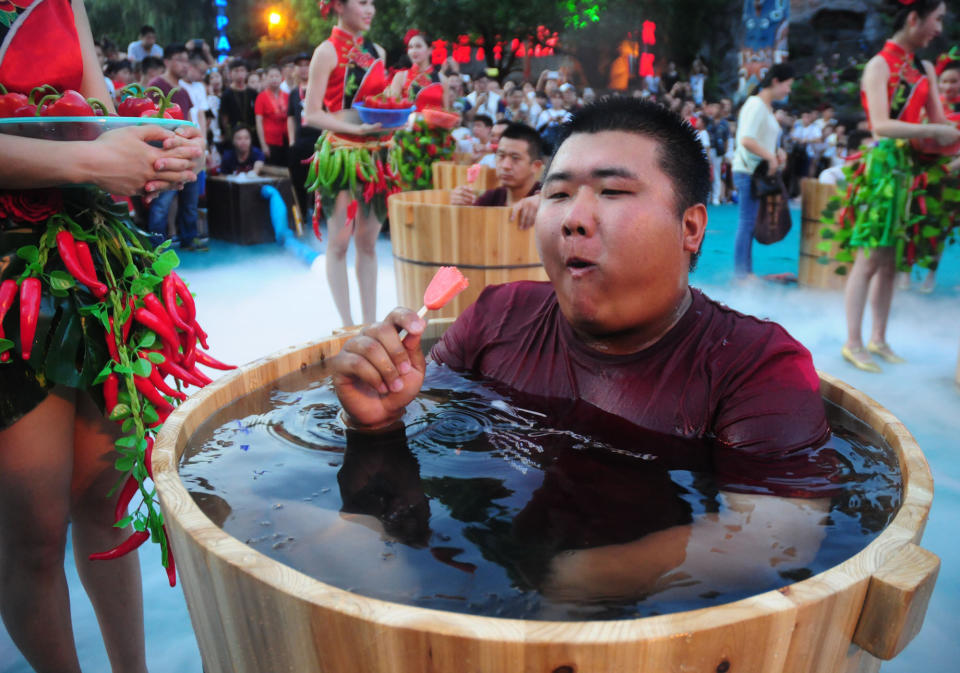 A man sitting in an ice bucket eats pepper ice-creams during a competition at Song Dynasty Town on July 20, 2016 in Hangzhou, Zhejiang Province of China.&nbsp;