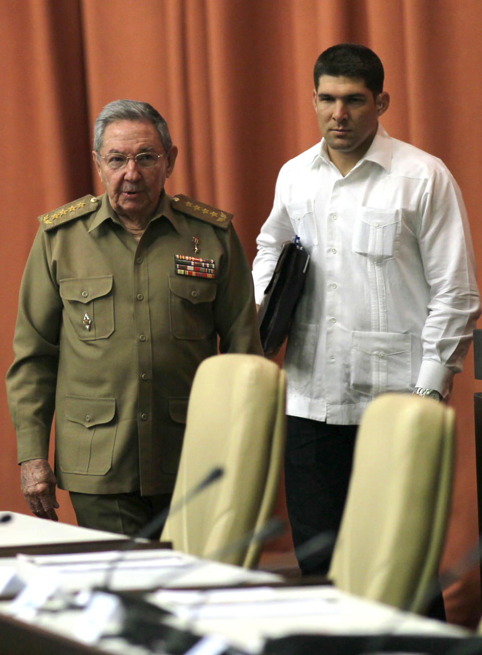 Accompanied by his personal assistant and grandson, Raul Guillermo Rodriguez Castro, right, Cuba's President Raul Castro arrives for an extraordinary session at the National Assembly for a vote that overhauls the foreign investment law, in Havana, Cuba, Saturday, March. 29, 2014. Cuban lawmakers approved a law Saturday that aims to make it more attractive for foreign investors to do business in and with the country, a measure seen as vital if the island's struggling economy is to improve. (AP Photo/Cubadebate, Ismael Francisco)