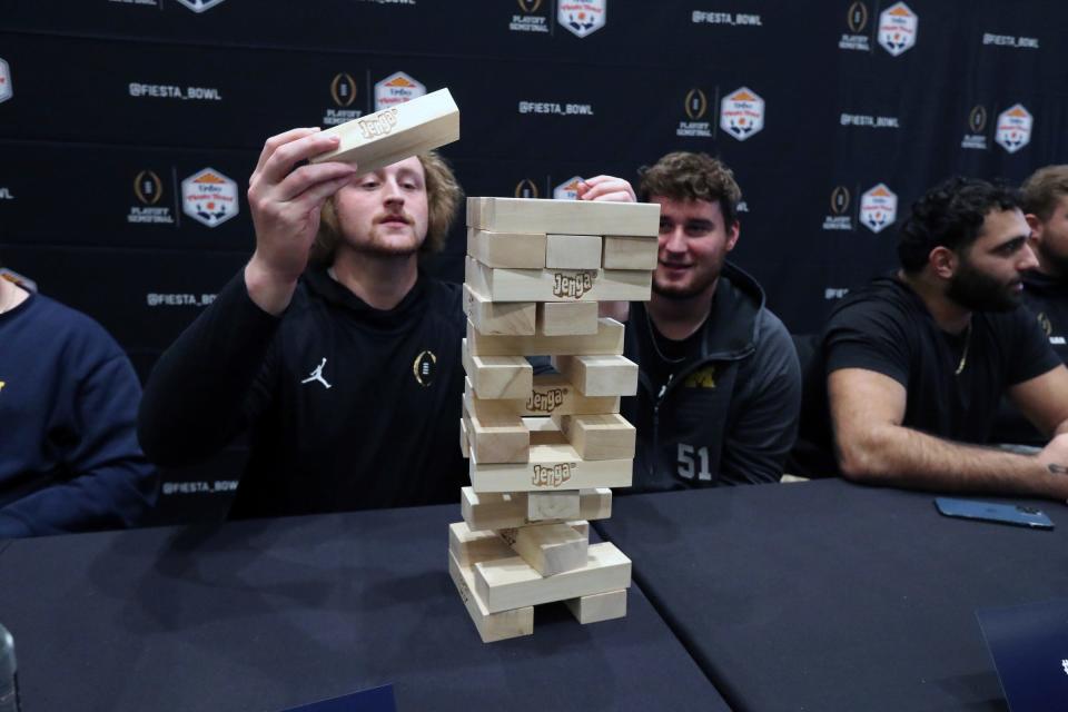 Michigan linebacker Kechaun Bennett, right, and offensive lineman Greg Crippen play a game of Jenga during media day held before the Fiesta Bowl against TCU on Thursday, Dec. 29, 2022, in Scottsdale, Arizona.