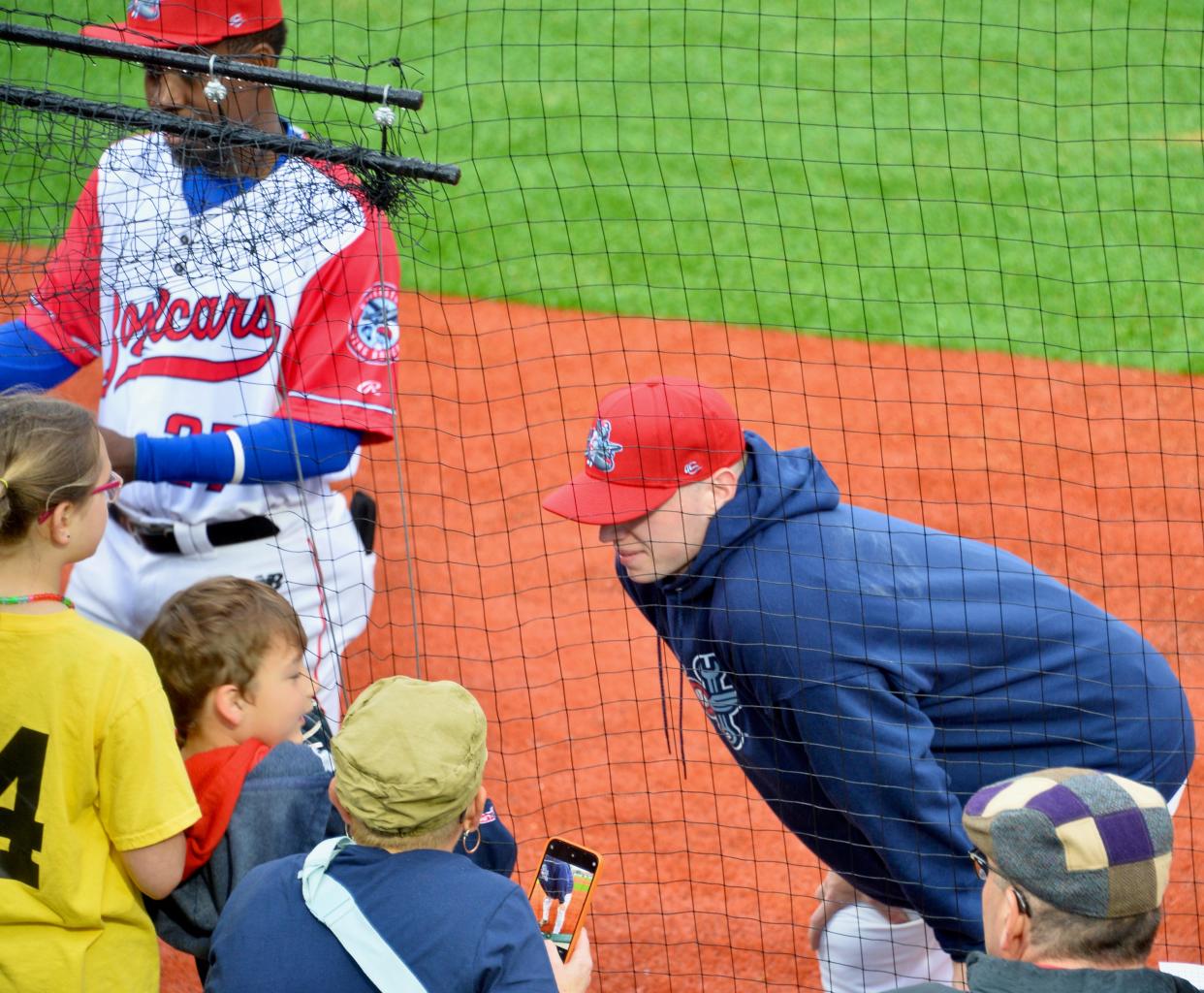 An unidentified Flying Boxcars player talks to fans before the start of the team's inaugural home game while outfielder Eury Perez, left, signs autographs.