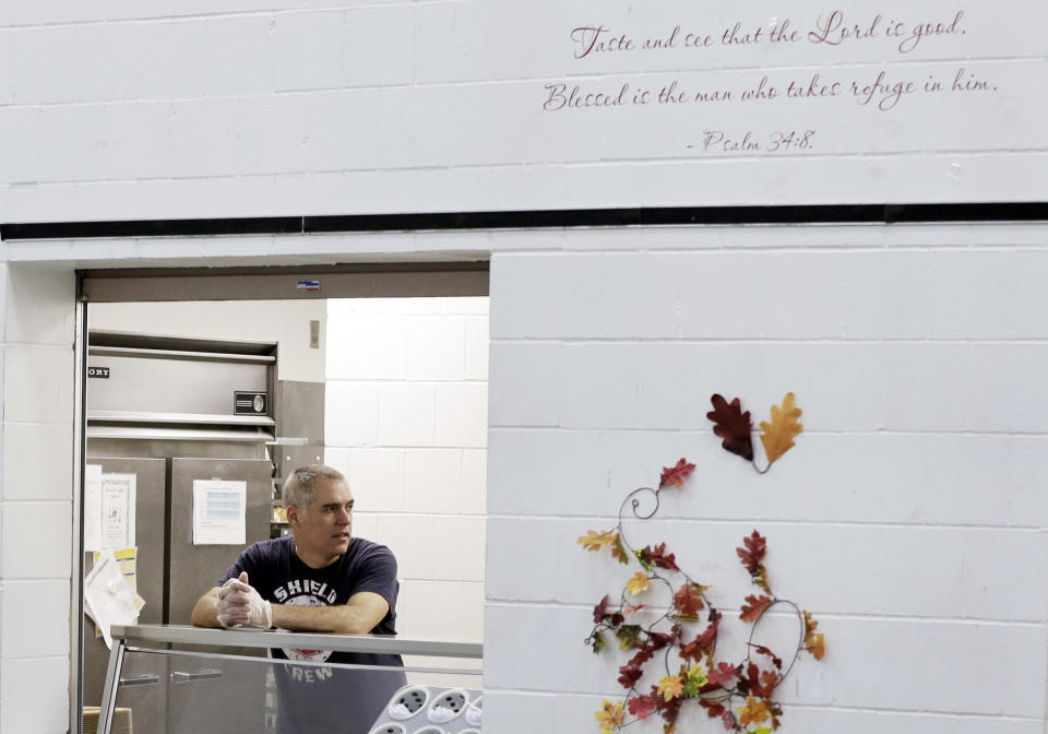 In this Nov. 14, 2013 photo, a Bible verse is written on the wall where chef Jeff Ansorge waits to serve lunch at the Salvation Army Eastside Corp Community Center in St. Paul, Minn. Ansorge, who used to command a staff of 17 at a posh downtown Minneapolis restaurant making nearly $80,000 a year, gave it all up to become the cook in charge of a Salvation Army soup kitchen where the meals are free. (AP Photo/Jim Mone)