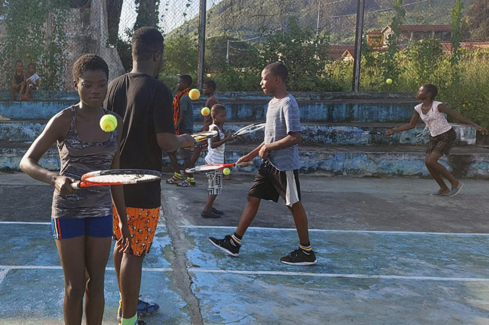 In this photo provided by Sam Jalloh, children in Sierra Leone participate in a tennis lesson in October 2021. Jalloh zig-zagged across West Africa in 2021 coaching tennis to kids. He took with him rackets, balls and a cellphone loaded with photos and videos of a pro player in action to inspire the youngsters. The player was new U.S. tennis star Frances Tiafoe. The move to encourage young Africans by showing them images of Tiafoe, an American with Sierra Leone heritage, has paid off big time. (Sam Jalloh via AP)