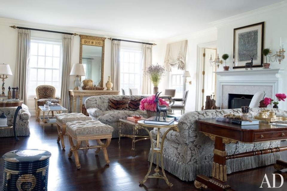 In designer Alex Papachristidis's <a rel="nofollow noopener" href="https://www.architecturaldigest.com/story/alex-papachristidis-hamptons-family-home-article?mbid=synd_yahoo_rss" target="_blank" data-ylk="slk:Hamptons living room;elm:context_link;itc:0;sec:content-canvas" class="link ">Hamptons living room</a>, which is painted in Benjamin Moore's Linen White, 19th-century gilded stools are placed next to sofas upholstered in a Clarence House fabric.