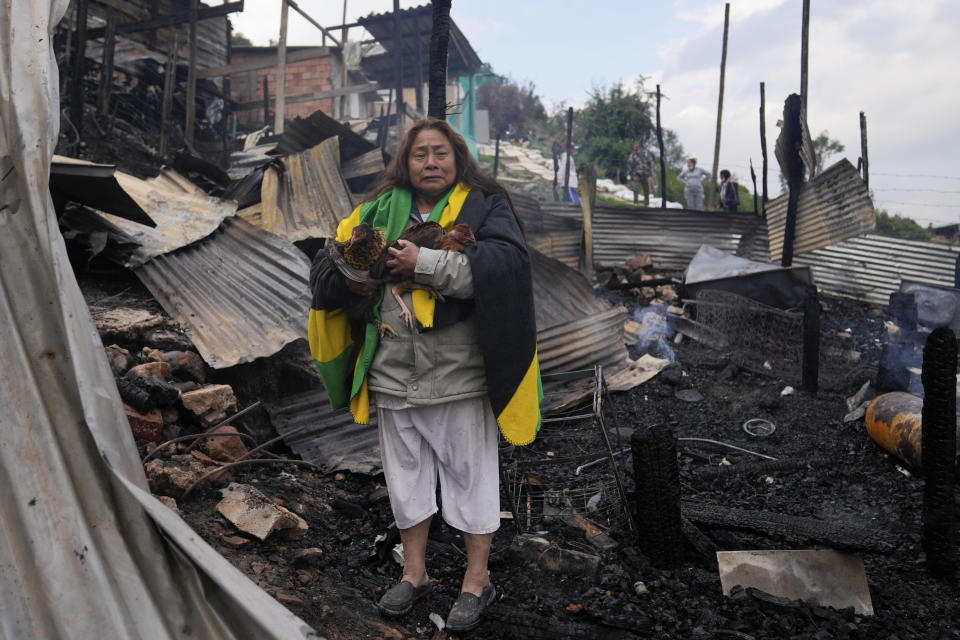 Verónica Kupto junto a las gallinas rescatadas entre los escombros carbonizados de su casa después de un incendio en Bogotá, Colombia, el viernes 8 de marzo de 2024. (AP Foto/Fernando Vergara)