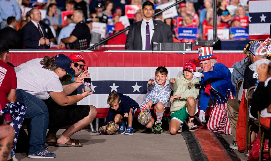 Duane Schwingel, right, dressed as Uncle Sam, poses for a photo with children as former president Donald Trump speaks during a rally at Wilmington International Airport on Friday, Sept. 23, 2022.