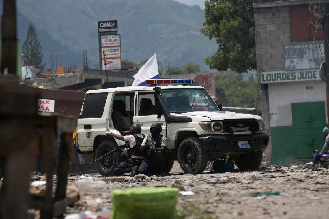 Police officers take cover as protesters throw rocks at them during a protest to demand that Haitian Prime Minister Ariel Henry step down and a call for a better quality of life in Port-au-Prince, Haiti, Wednesday, Sept. 7, 2022.