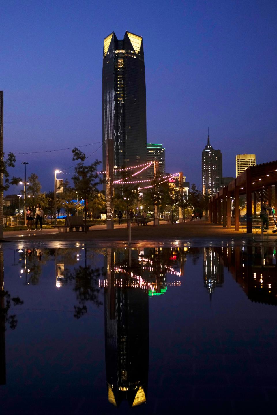 The downtown skyline of Oklahoma City, featuring the Devon Energy Tower, is reflected in the fountains on the east side of Scissortail Park.