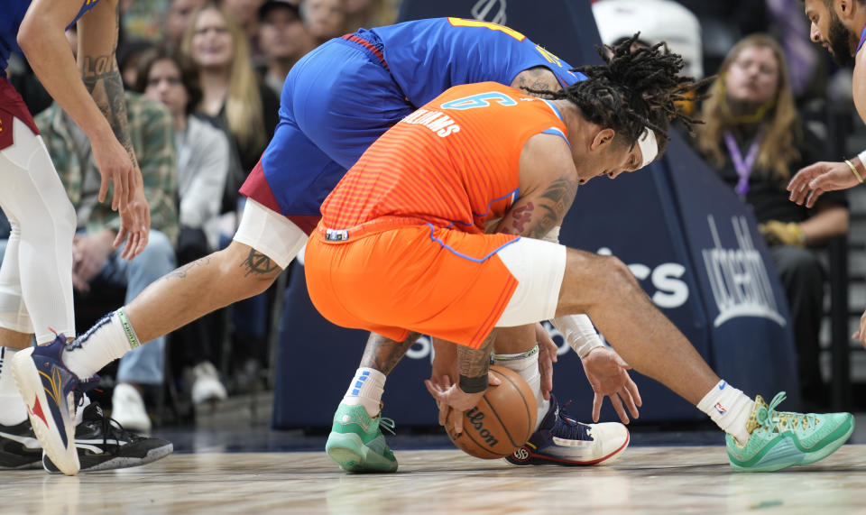 Oklahoma City Thunder forward Jaylin Williams, front, fights for control of the ball with Denver Nuggets forward Aaron Gordon, back, in the first half of an NBA basketball game Saturday, Dec. 16, 2023, in Denver. (AP Photo/David Zalubowski)