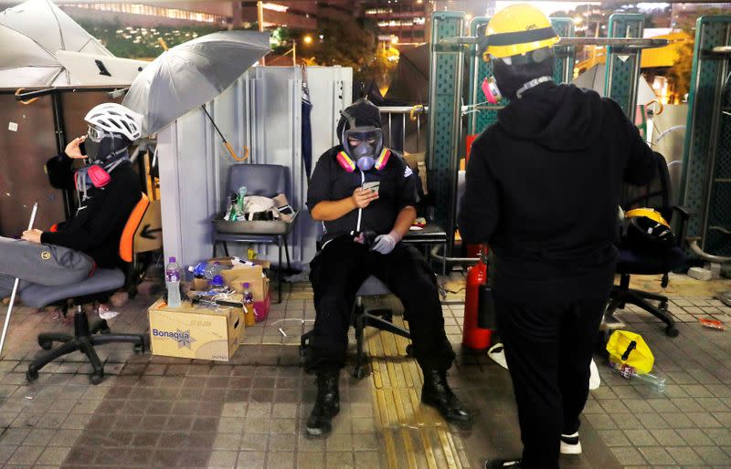 Pak, an anti-government protester, checks his mobile phone as he guards a bridge outside the Polytechnic University in Hong Kong