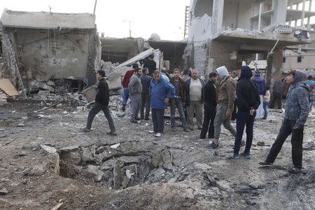 People inspect a site after hit by what activists said were air strikes by forces loyal to Syria's President Bashar al-Assad in Raqqa, eastern Syria, which is controlled by the Islamic State November 25, 2014. REUTERS/Nour Fourat