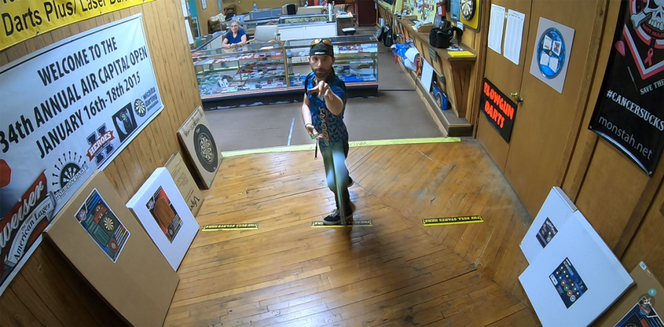 Josh Foster lines up a shot while practicing his dart throwing skills in the store’s showroom.