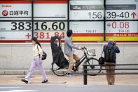 People pass by an electronic stock board showing Japan's Nikkei 225 index, left, and U.dollar/Japanese yen conversion rate at a securities firm Tuesday, April 30, 2024, in Tokyo. Asian shares mostly rose Tuesday, as investors kept their eyes on potentially market-moving reports expected later this week.(AP Photo/Eugene Hoshiko)