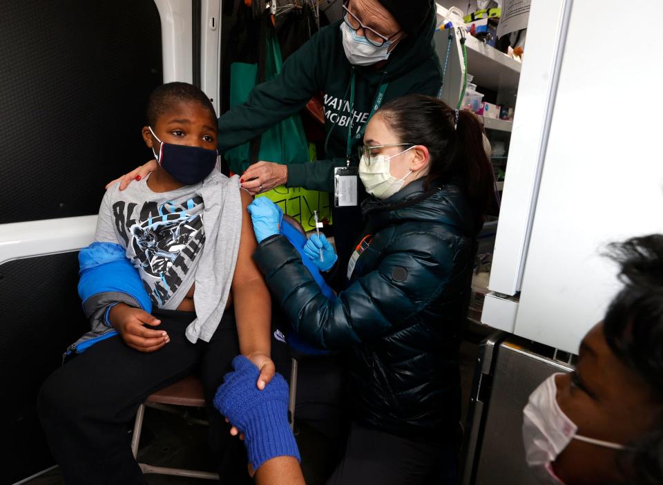 Sharonda Robinson, 37, of Detroit, holds her 9-year-old son, Aiden Robinson's, hand as Marya Rosenthal, a registered nurse with the Wayne Health Mobile Unit, and Monique Rickel, a registered nurse with the University of Michigan, give him his first COVID-19 Pfizer vaccine on Saturday, Dec. 11, 2021