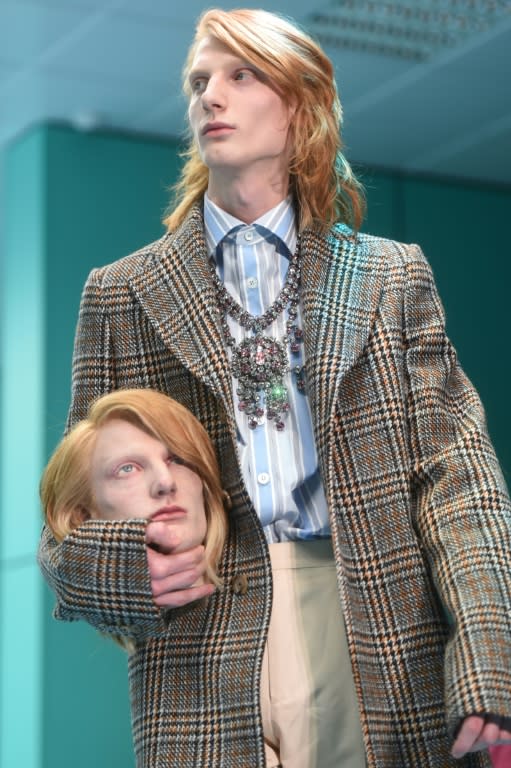 A Gucci model holds a replica of his own head on the runway