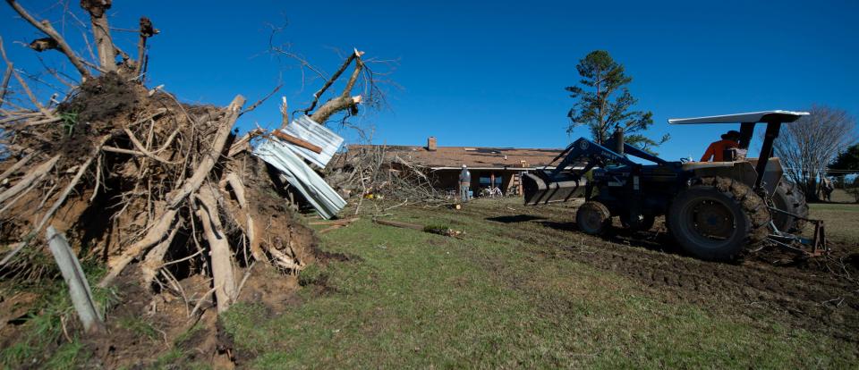 Family and friends clear a huge pecan tree, thought to be about 100 years old, off of the home of Robert and Brenda Burdine in the Mathiston community in Choctaw County, Miss., Wednesday, Nov. 30, 2022. A storm front moved through the state Tuesday into early Wednesday causing tornadoes throughout the state.