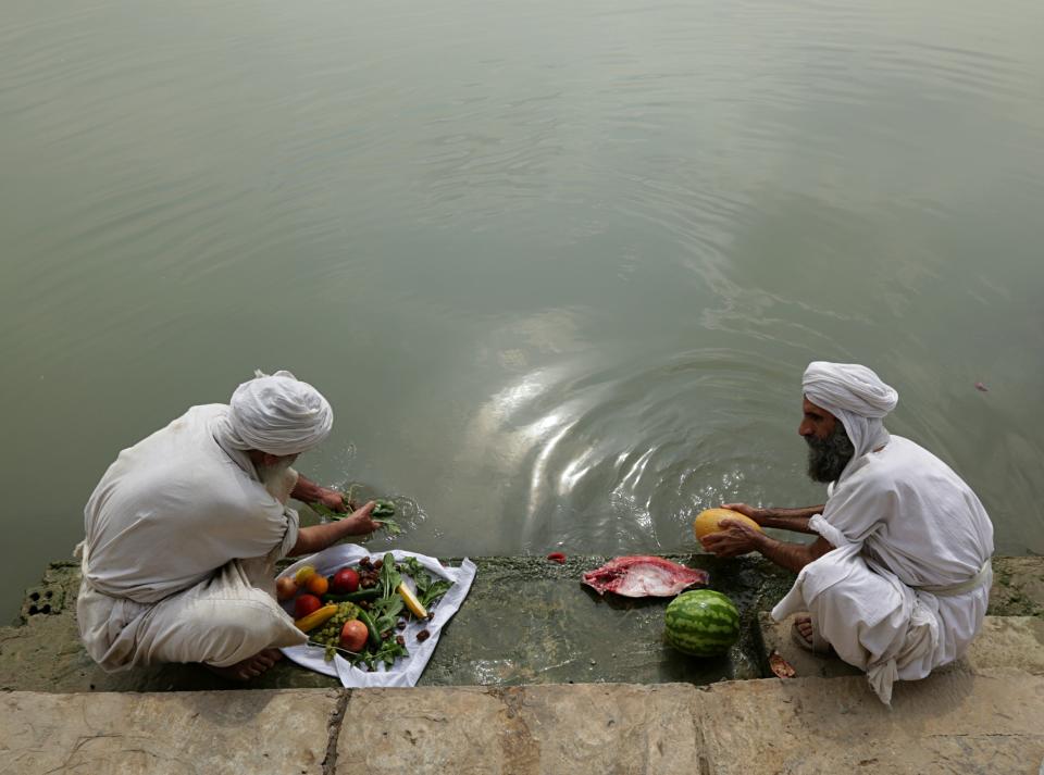 In this Sunday, Oct. 14, 2018 photo, followers of the obscure and ancient Mandaean faith wash food with river water along a strip of embankment on the Tigris River reserved for them, in Baghdad, Iraq. Every Sunday worshippers bathe themselves in the waters to purify their souls. But unlike in ancient times, the storied river that runs through Baghdad is fouled by the smells of untreated sewage and dead carp, which float by in the fast-moving current. (AP Photo/Hadi Mizban)