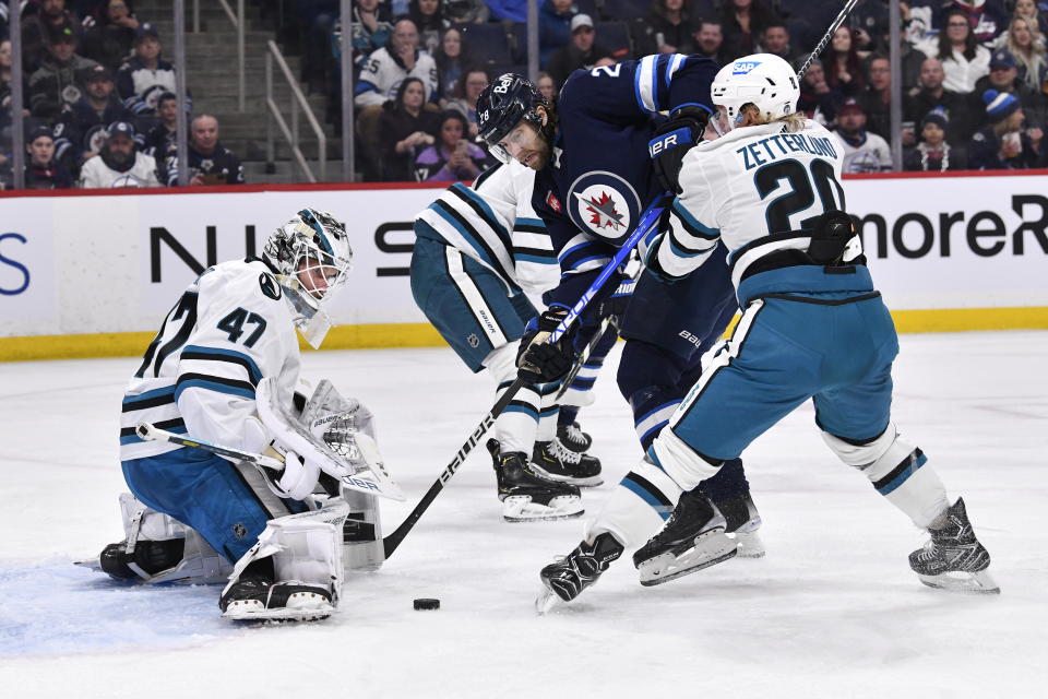 San Jose Sharks goaltender James Reimer (47) makes a a save on Winnipeg Jets' Kevin Stenlund (28) as Fabian Zetterlund defends during the second period of an NHL hockey game, in Winnipeg, Manitoba, on Monday March 6, 2023. (Fred Greenslade/The Canadian Press via AP)