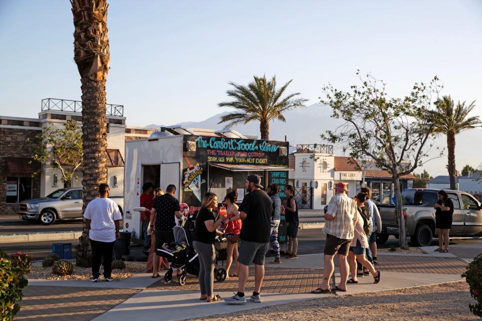 People gather to purchase food and beverages from various food trucks on Palm Drive and Pierson Boulevard for the weekly Friday Nights on Pierson event in downtown Desert Hot Springs, Calif., on Friday, May 12, 2023.