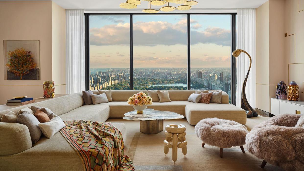 a living room with a large window overlooking central park, large sectional sofa with a colorful throw, clocktail table, chair and ottoman in fuzzy fabric, curved floor lamp, gold pendant, wall art and sculptures