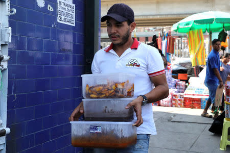 Samuel Gomez, a migrant from Venezuela, carries food for his restaurant 'Areperu' at Gamarra textile cluster in Lima's district of la Victoria in Lima, Peru, May 10, 2018. Picture taken May 10, 2018. REUTERS/Guadalupe Pardo