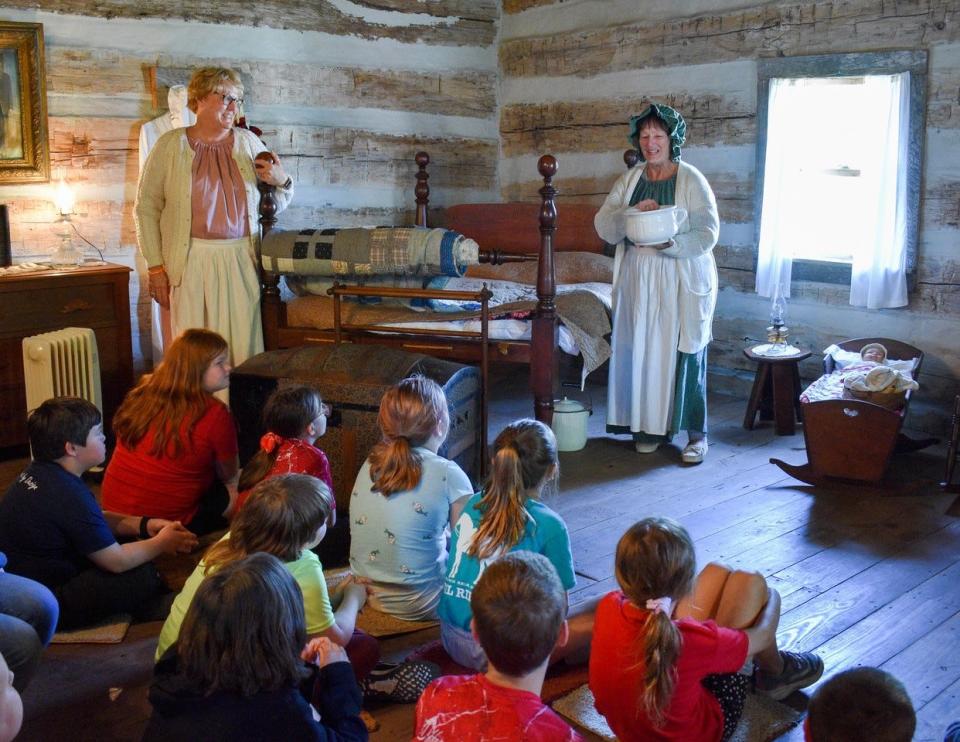 Dot Priesman, left, and Connie Fabian explain chamber pots to third grade visitors inside the Oak Harbor Log Cabin. The cabin originally sat on a farm owned by Priesman’s grandfather and was donated to the village by her parents.