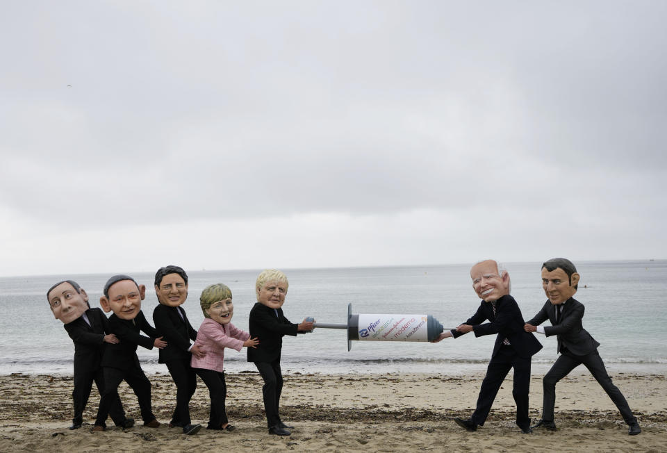 Activists wearing giant heads of the G7 leaders tussle over a giant COVID-19 vaccine syringe during an action on the beach in Falmouth, Cornwall, England, during an action by NGO's on Friday, June 11, 2021. Leaders of the G7 begin their first of three days of meetings on Friday in Carbis Bay, in which they will discuss COVID-19, climate, foreign policy and the economy. Depicted from left to right, Italy's Prime Minister Mario Draghi, Japan's Prime Minister Yoshihide Suga, Canadian Prime Minister Justin Trudeau, German Chancellor Angela Merkel, British Prime Minister Boris Johnson, U.S. President Joe Biden and French President Emmanuel Macron. (AP Photo/Kirsty Wigglesworth)