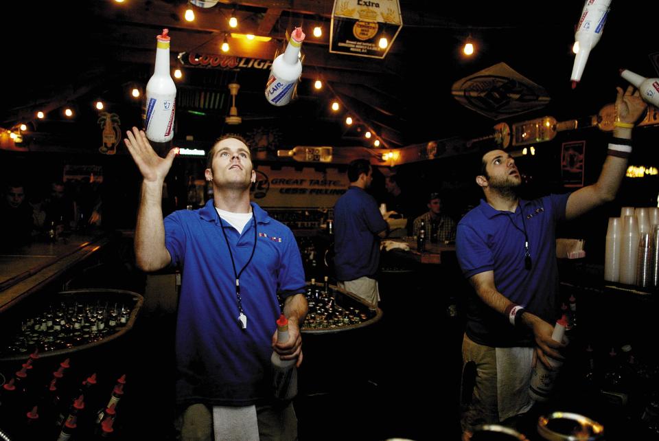 Kahunaville bartenders Alex Masci, left, and Ray Speight put on a show at The Deck of Kahunaville in Wilmington on Thursday, Aug. 5, 2004.