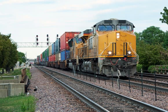 Two yellow locomotives hauling double-stacked freight train.