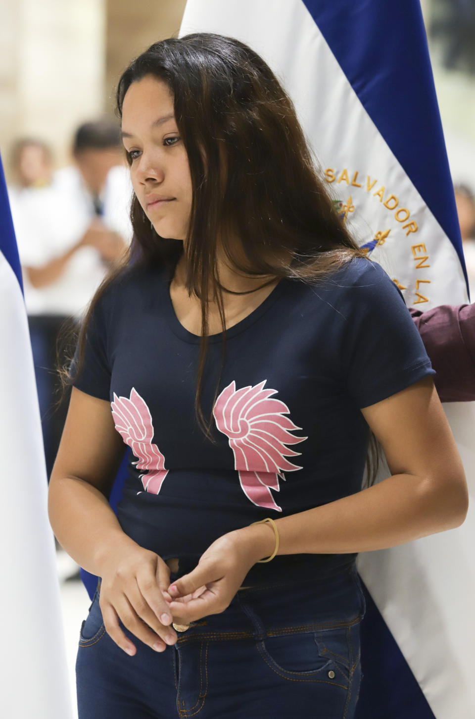 Tania Vanessa Avalos stands nearby as a government official speaks at a press conference at the airport, after her arrival in San Salvador, El Salvador, Friday, June 28, 2019. Avalos is the wife of the young man who drowned alongside his 23-month-old daughter while trying to cross the Rio Grande into Texas on Sunday, June 23. (AP Photo/Salvador Melendez)