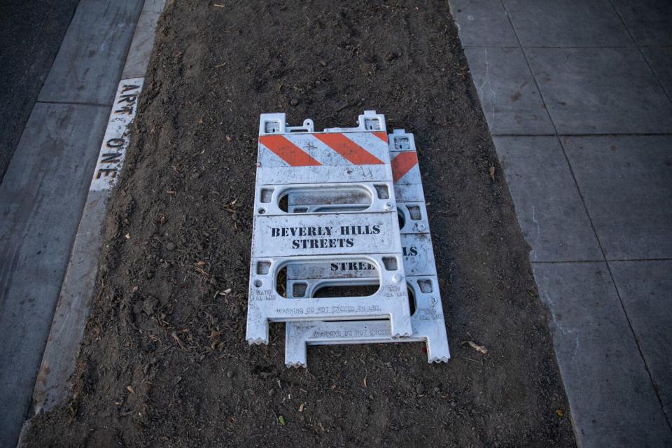 Caution signs lie in an empty sidewalk planter