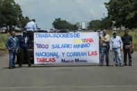 FILE PHOTO: Workers of CVG hold a banner that reads "Workers of Guayana. 1800 minimun wage and adjust the pay scales" during a protest in Puerto Ordaz