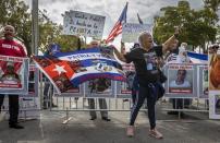 Protestors shout slogans while demonstrating against the Cuban government in front of LoanDepot Park prior to a World Baseball Classic game between Cuba and the United States, Sunday, March 19, 2023, in Miami. The sign at back center left reads, “Against Fidel? Even in baseball!” The writing on the flag reads “Fatherland and life. Long live Free Cuba.” The sign at back center right reads,“Diaz Canel and Raul Castro murderers.” (Jose A. Iglesias/Miami Herald via AP)