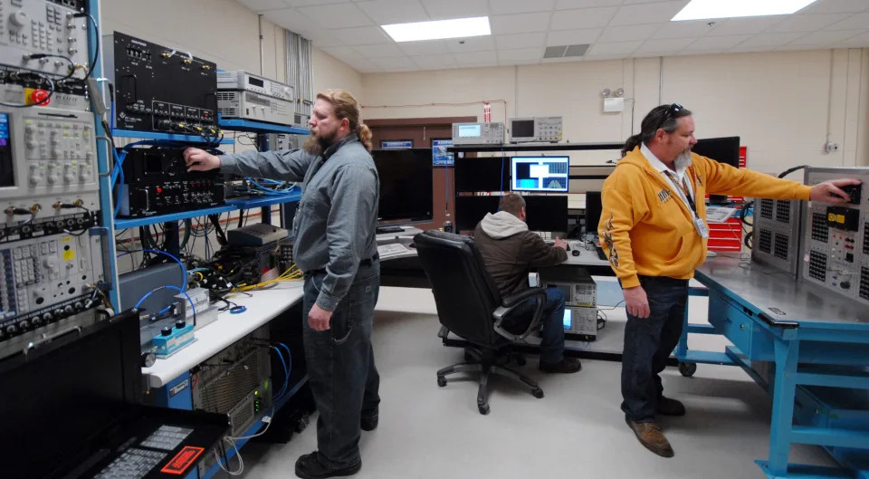 Contractors with the 68th Electronic Warfare Squadron prepare the Advanced Integrated Defense Electronic Warfare System test lab for a test run. Members of the Advanced Systems Flight of the 68th EWS work closely with their foreign customers to facilitate future requirements so their mission data can be tailored to the ever-changing threat environment and define the customer’s necessities to build future products. <em>USAF</em>