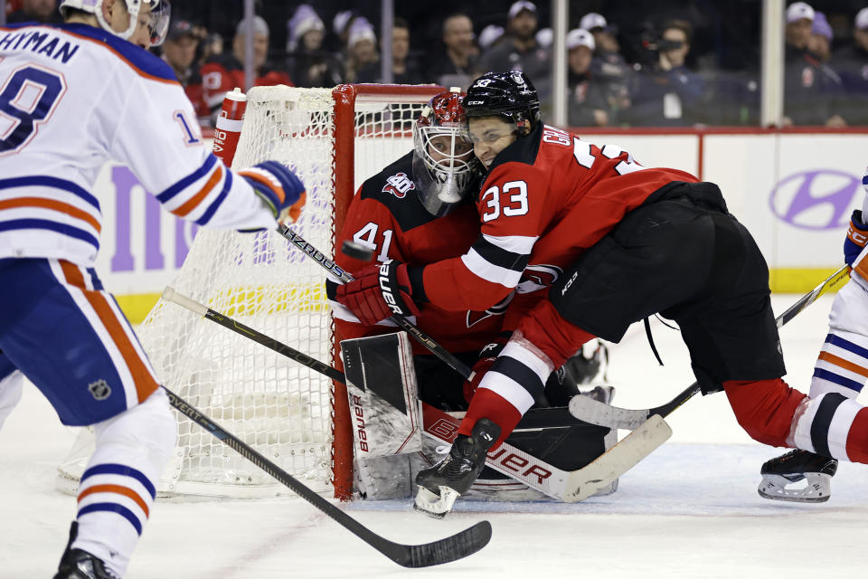 New Jersey Devils defenseman Ryan Graves (33) collides with his goaltender Vitek Vanecek while defending against Edmonton Oilers left wing Zach Hyman (18) during the third period of an NHL hockey game Monday, Nov. 21, 2022, in Newark, N.J. (AP Photo/Adam Hunger)