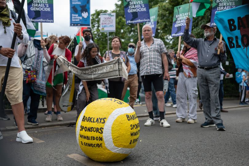 A tennis ball prop that says "Barclays Sponsors Wimbledon and Genocide" during the demonstration