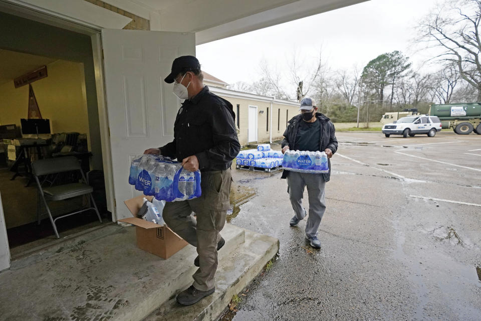 David Battaly with the Mississippi Emergency Management Agency, left, and Ralph Woullard, a member of the New Mt. Zion Missionary Baptist Church, carry cases of bottled water inside the church, Monday, March 1, 2021, at a Jackson, Miss., water distribution site on the church's parking lot. The bottled water as well as non-potable water was provided for area residents and was being distributed at seven sites in Mississippi's capital city — more than 10 days after winter storms wreaked havoc on the city's water system because the system is still struggling to maintain consistent water pressure, authorities said. (AP Photo/Rogelio V. Solis)