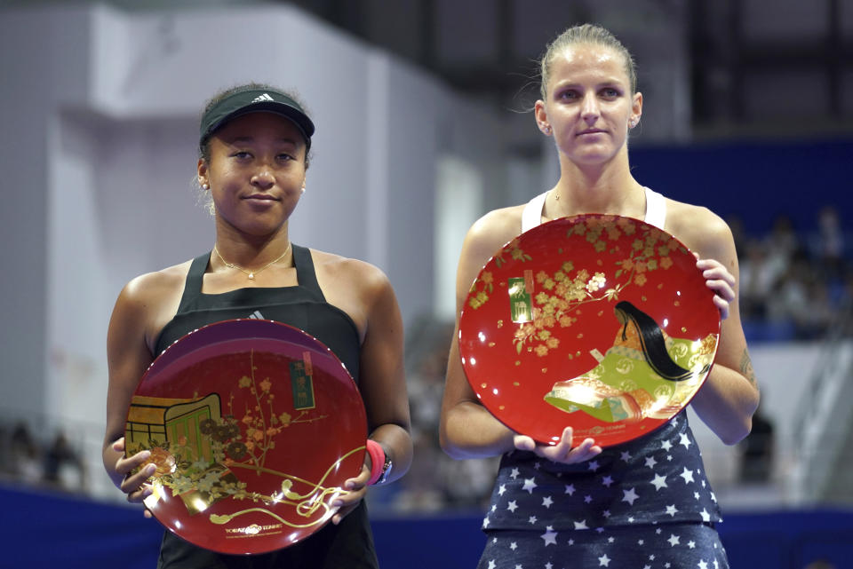 Karolina Pliskova, right, of Czech Republic, holds her champion trophy and Naomi Osaka, left, of Japan holds her runner-up trophy during the award ceremony of the Pan Pacific Open women's tennis tournament in Tokyo Sunday, Sept. 23, 2018. (AP Photo/Eugene Hoshiko)