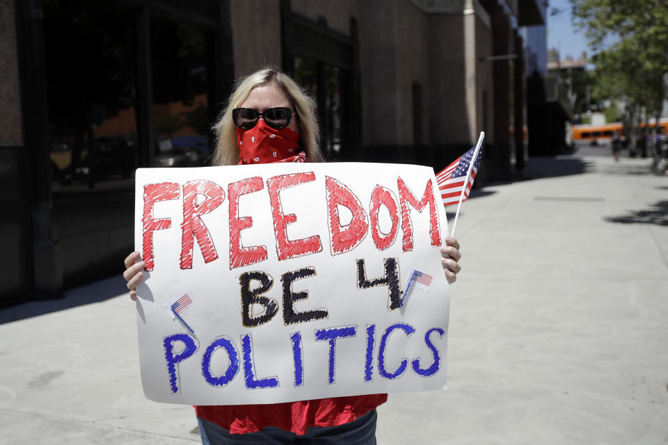 A protester holds a sign during a rally calling for an end to California Gov. Gavin Newsom's stay-at-home orders amid the COVID-19 pandemic, Wednesday, April 22, 2020, outside of City Hall in downtown Los Angeles. (AP Photo/Marcio Jose Sanchez)