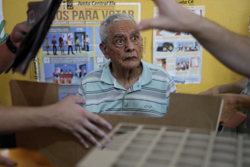 A voter is assisted by electoral official to cast his ballot during general elections in Santo Domingo, Dominican Republic, Sunday, May 19, 2024. (AP Photo/Matias Delacroix)