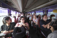 Passengers of the MS Westerdam sit in a busa after they disembarked from the cruise ship, owned by Holland America Line, at the port of Sihanoukville, Cambodia, Friday, Feb. 14, 2020. Hundreds of cruise ship passengers long stranded at sea by virus fears cheered as they finally disembarked Friday and were welcomed to Cambodia. (AP Photo/Heng Sinith)